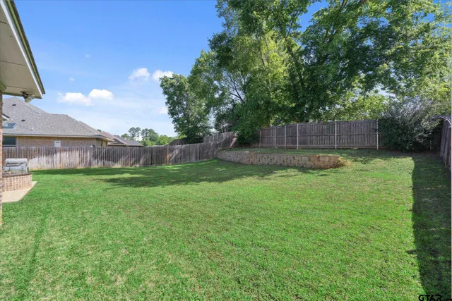 a view of a yard with a fence and trees