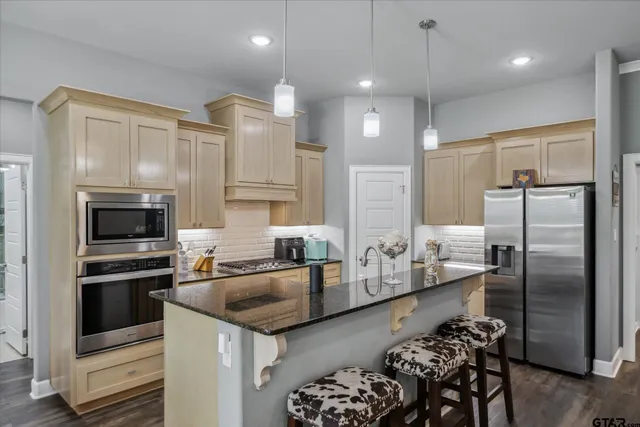 a kitchen with stainless steel appliances granite countertop a sink refrigerator and cabinets
