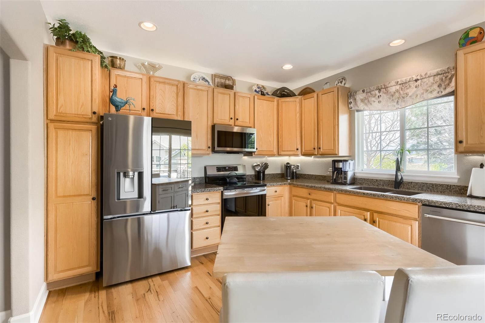 9006 Old Tom Morris Circle Highlands Ranch, CO 80129 - Photo 11 of 41 a kitchen with granite countertop a refrigerator a sink dishwasher with a dining table and chairs