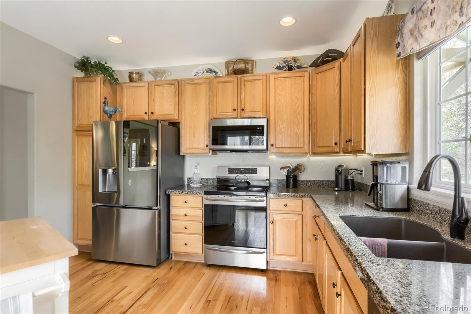 9006 Old Tom Morris Circle Highlands Ranch, CO 80129 - Photo 12 of 41 a kitchen with stainless steel appliances granite countertop a refrigerator a stove a sink and a microwave with wooden floor