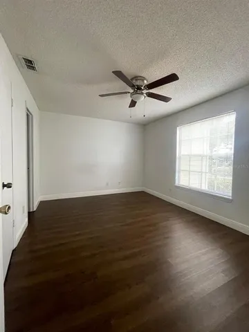 a view of empty room with wooden floor and fan