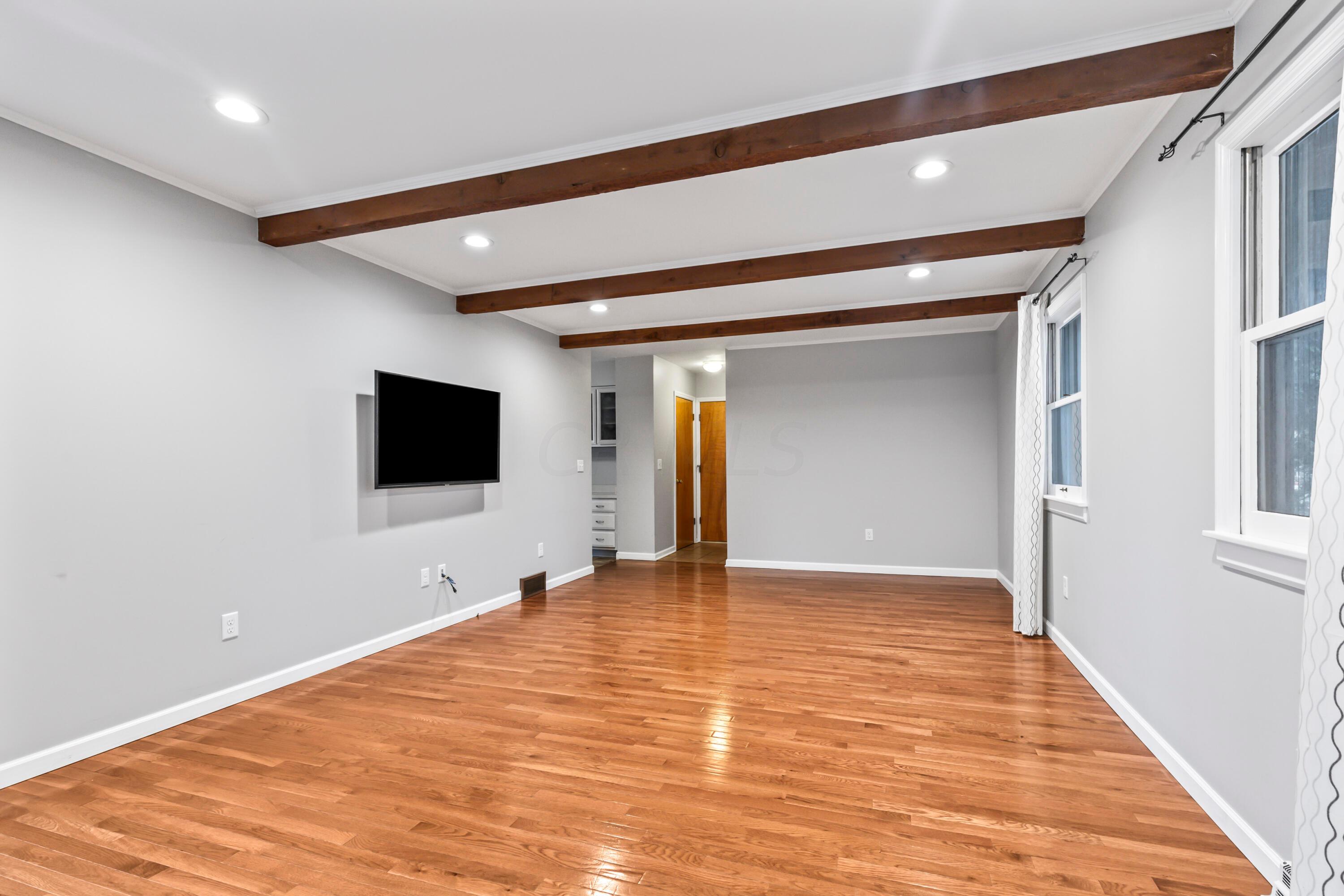 7020 Rieber Street Columbus, OH 43085 - Photo 19 of 40 • New hardwood flooring ~ 2017 • Grey painted walls • Decorative ceiling beams • Can lighting • Wood burning, white painted brick fireplace • Drapes are negotiable • New double sliding doors to patio • TV & mount are negotiable