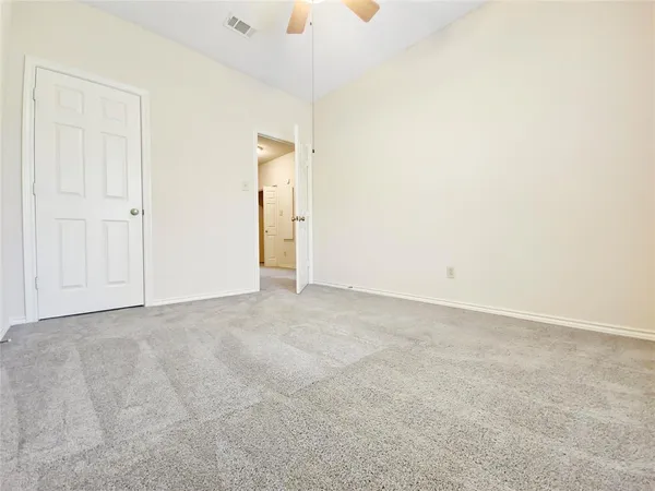 an empty room with a chandelier fan and windows
