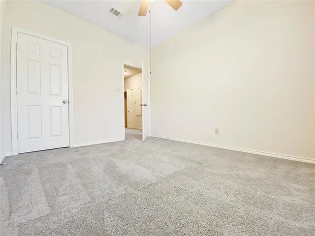 an empty room with a chandelier fan and windows
