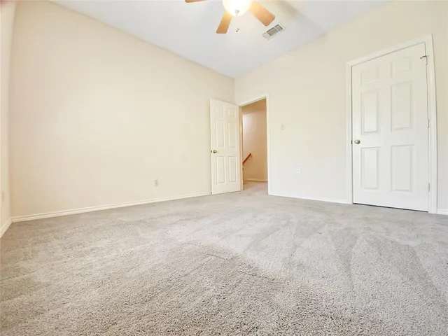 an empty room with a chandelier fan and windows