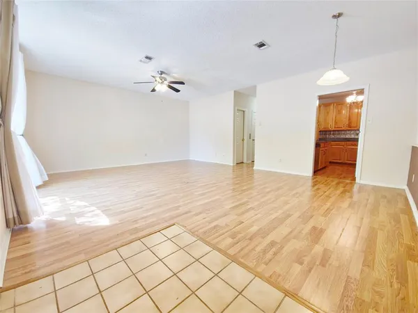 a view of an empty room and chandelier fan