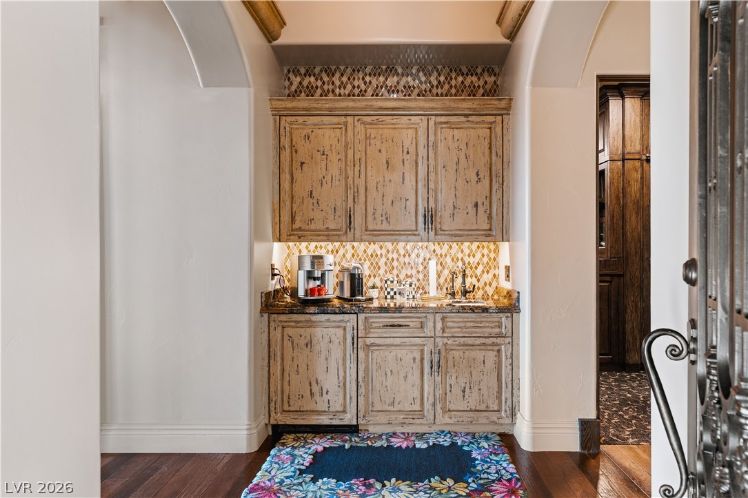 1123 Christian Road Henderson, NV 89002 - Photo 19 of 94 A well-appointed dry bar features distressed cabinetry, a patterned tile backsplash, and dark granite countertops, perfect for entertaining.