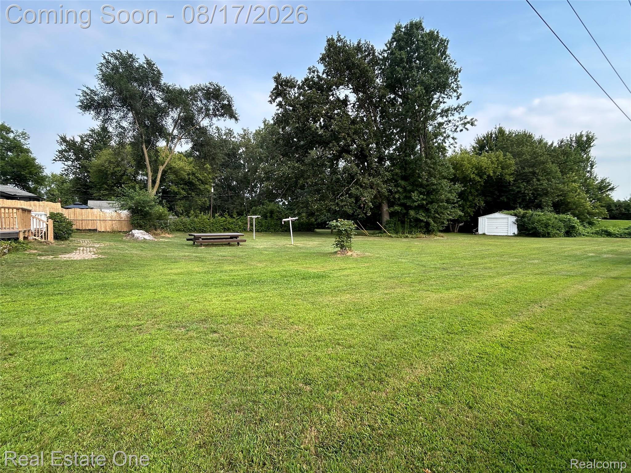 22967 Northline Road Taylor, MI 48180 - Photo 22 of 22 Expansive green lawn, wood deck, natural wood privacy fencing, mature trees, and a white storage shed