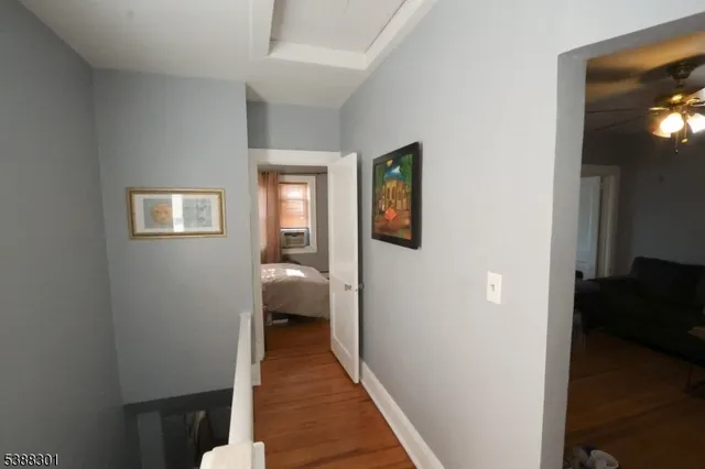 a view of a hallway with wooden floor and a living room