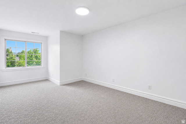 1429 Chateau Ridge Way Sandy, UT 84092 - Photo 19 of 22 Spacious room featuring light gray carpeting, crisp white walls, a large window with white framing, and a flush-mount ceiling light fixture