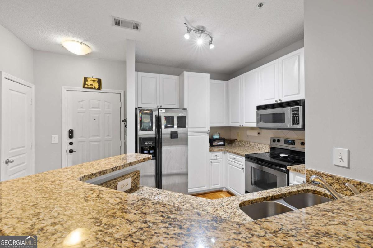 10 Perimeter Summit Boulevard Brookhaven, GA 30319 - Photo 10 of 20 a kitchen with stainless steel appliances kitchen island granite countertop a sink refrigerator and microwave