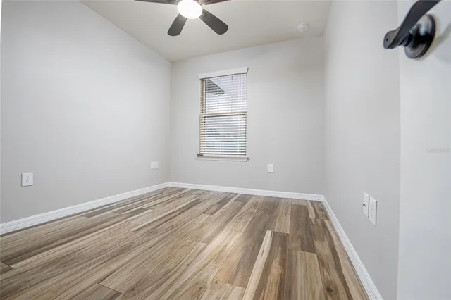 an empty room with a window and ceiling fan
