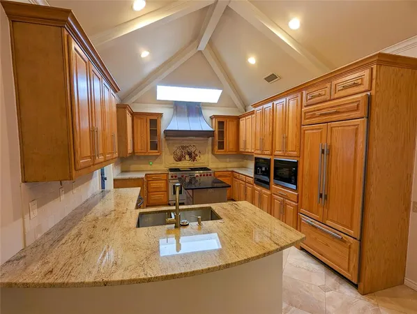 a kitchen with kitchen island granite countertop a sink appliances and cabinets