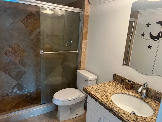 a bathroom with a granite countertop toilet sink and shower