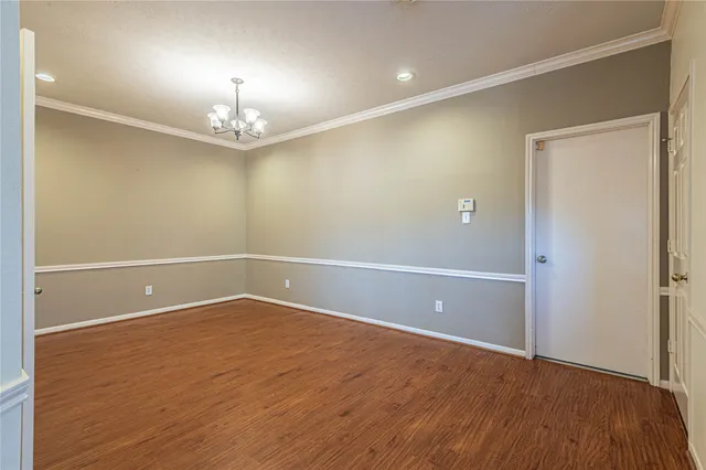 an empty room with wooden floor and chandelier