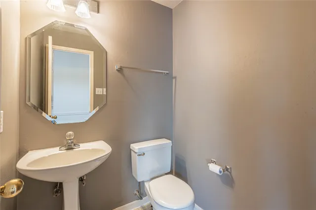 a bathroom with a toilet a sink and mirror