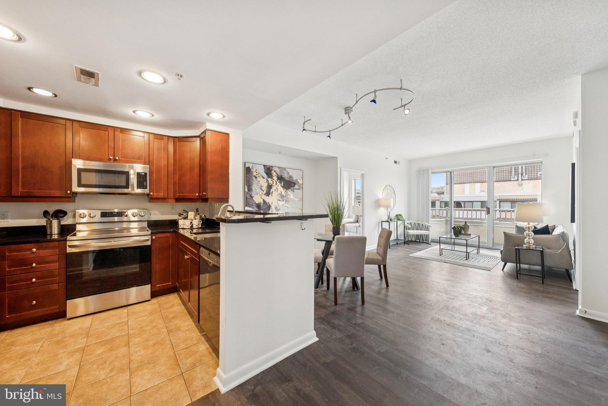 1111 11th Street Northwest, Unit 901 Washington, DC 20001 - Photo 12 of 24 a kitchen with stainless steel appliances kitchen island granite countertop a refrigerator a stove top oven a sink a dining table and chairs with wooden floor