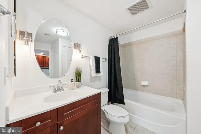 a bathroom with a bathtub shower sink vanity mirror and toilet