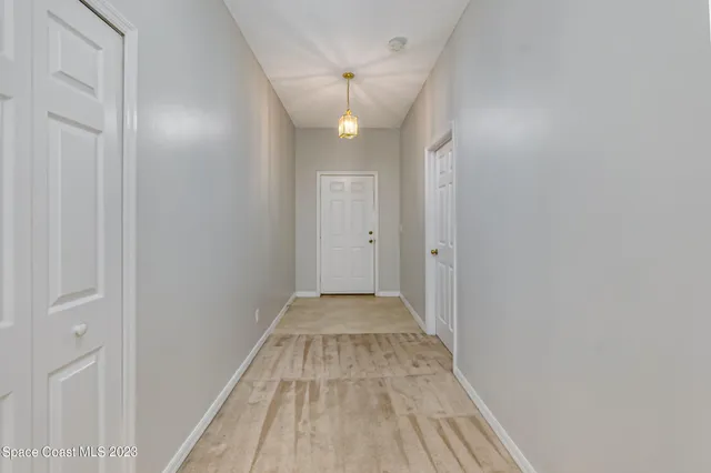 a view of a hallway with wooden floor and a bathroom
