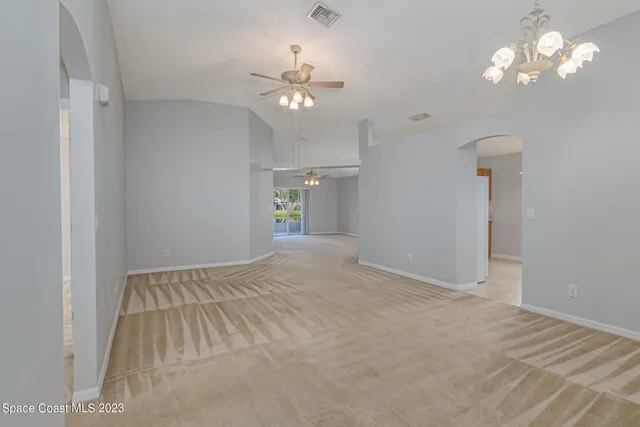 a view of an empty room with a chandelier fan