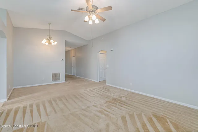 a view of an empty room with a chandelier fan