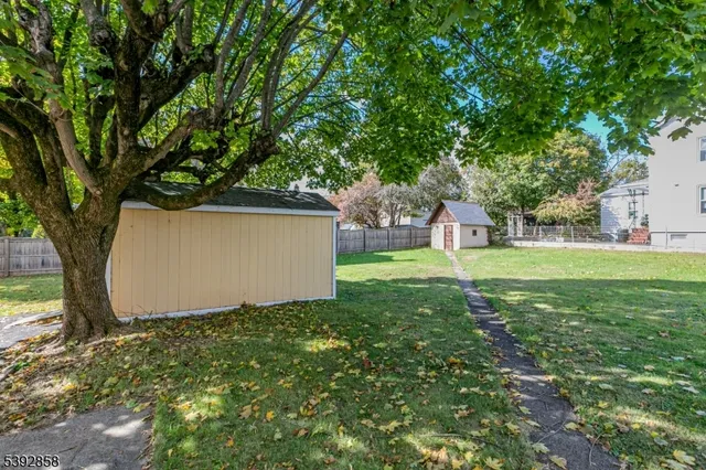 a view of a tree in front of a house with a big yard and large trees