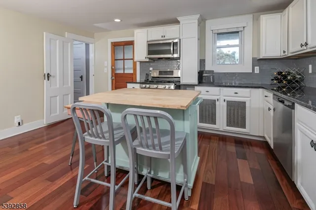 a kitchen with stainless steel appliances granite countertop a kitchen island hardwood floor and a sink