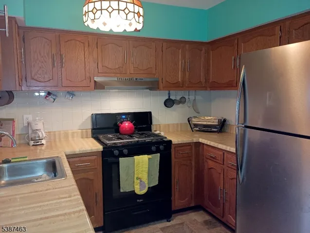 a kitchen with stainless steel appliances granite countertop a refrigerator and a stove top oven