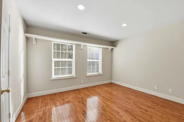 an empty room with wooden floor and windows