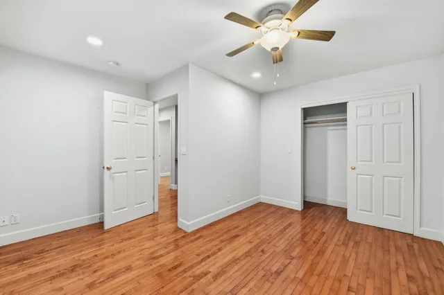 an empty room with wooden floor and a ceiling fan