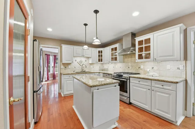 a kitchen with stainless steel appliances granite countertop a stove and white cabinets