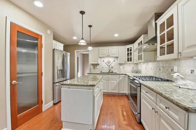 a kitchen with stainless steel appliances granite countertop a sink a stove and a refrigerator