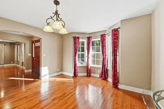 a view of an empty room with wooden floor and windows