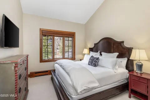 a bedroom with a bed and a flat tv screen on dresser