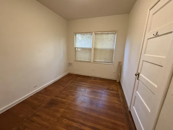 an empty room with wooden floor and window