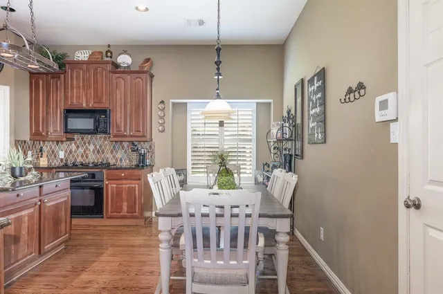 a kitchen with stainless steel appliances granite countertop a stove a sink dishwasher a dining table and chairs with wooden floor