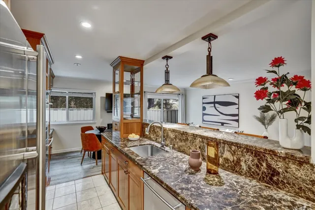 a kitchen with stainless steel appliances granite countertop a sink dishwasher a stove and a dining table next to a window