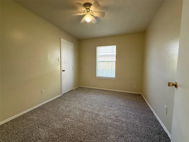an empty room with a chandelier fan and windows