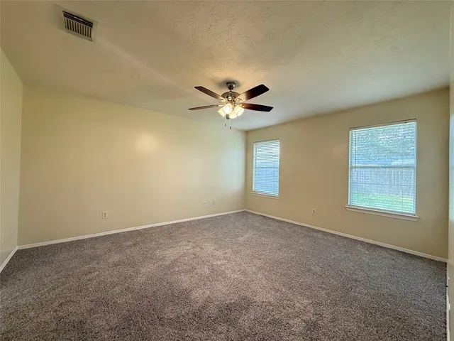an empty room with a window and a ceiling fan