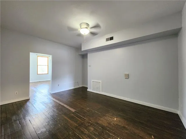 an empty room with wooden floor chandelier fan and windows