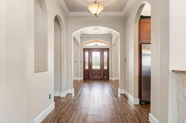 a view of a hallway with wooden floor and a chandelier