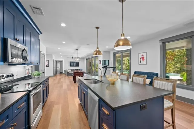 a kitchen with stainless steel appliances granite countertop wooden cabinets a stove a sink a oven and a refrigerator