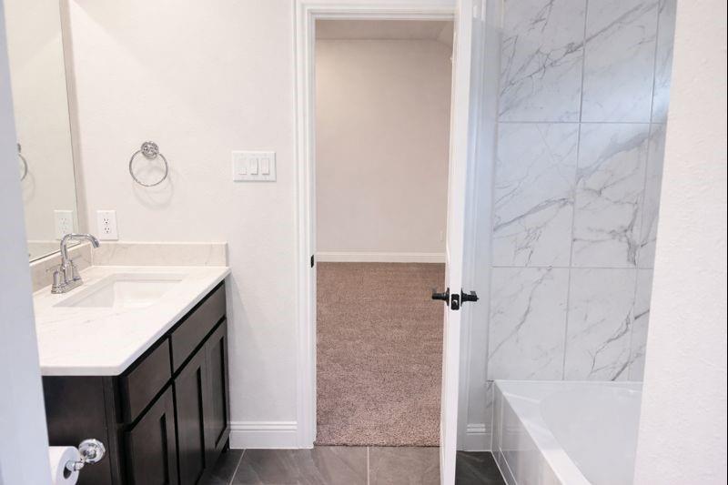 6825 Entwistle Road Frisco, TX 75034 - Photo 19 of 25 Bathroom featuring a vanity with a white countertop, chrome faucet, and dark wood cabinetry