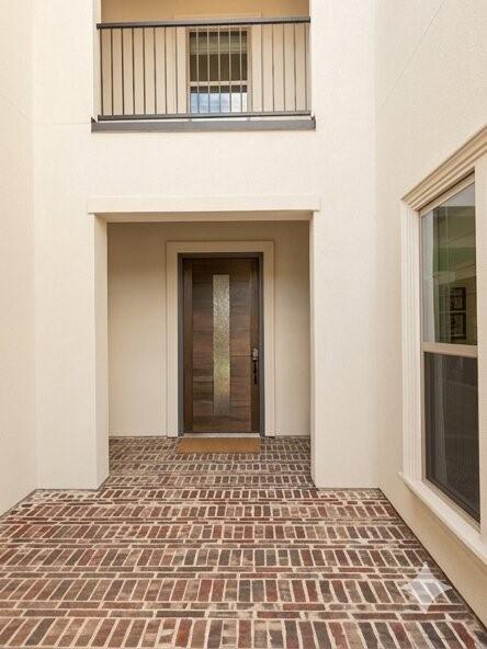 6825 Entwistle Road Frisco, TX 75034 - Photo 2 of 25 The property entrance features a distinctive brick-patterned floor and a modern wooden door with a frosted glass insert