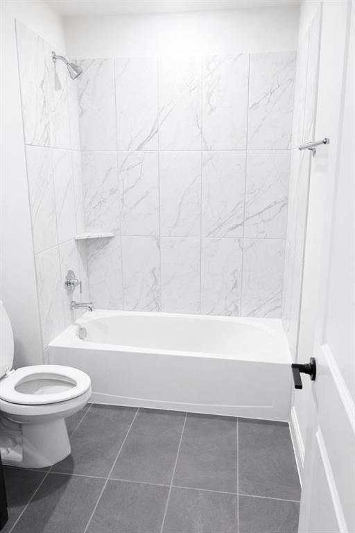 6825 Entwistle Road Frisco, TX 75034 - Photo 23 of 25 Bathroom featuring a bathtub with a shower, white tiled walls with a subtle pattern, and dark tiled floors