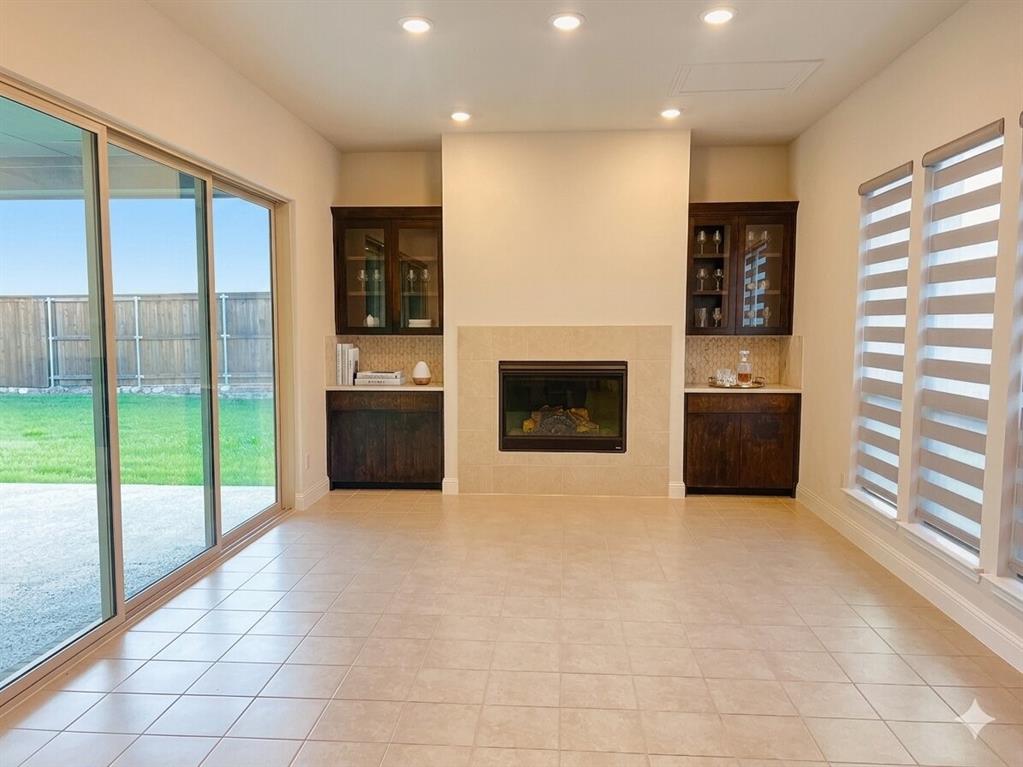 6825 Entwistle Road Frisco, TX 75034 - Photo 3 of 25 The living area features tiled flooring, a fireplace with a stone surround, and built-in cabinetry with glass display doors