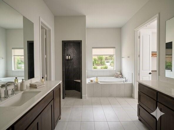 6825 Entwistle Road Frisco, TX 75034 - Photo 6 of 25 The bathroom features a built-in bathtub, a walk-in shower with dark tile, and a double vanity with dark wood cabinetry and light countertops