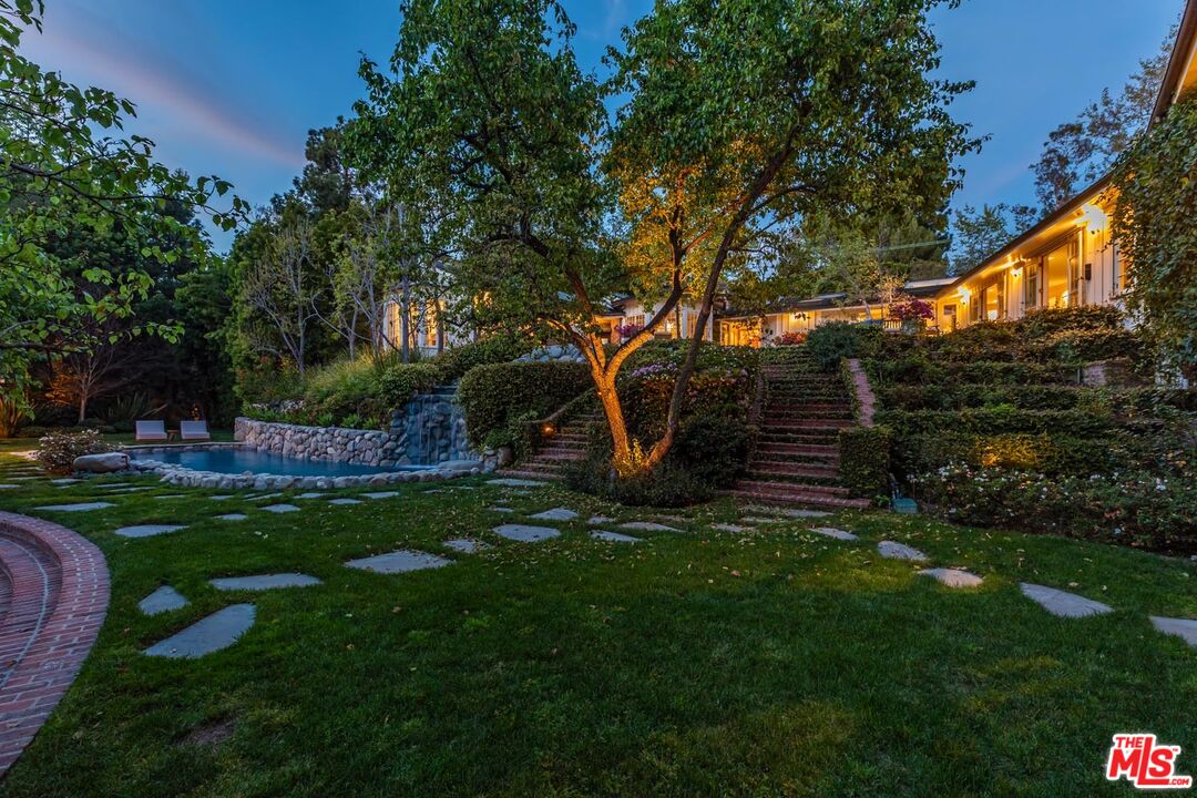 a view of backyard with table and chairs and potted plants and large trees