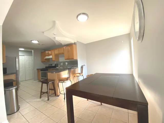 a kitchen with granite countertop a stove a sink a refrigerator dining table and chairs