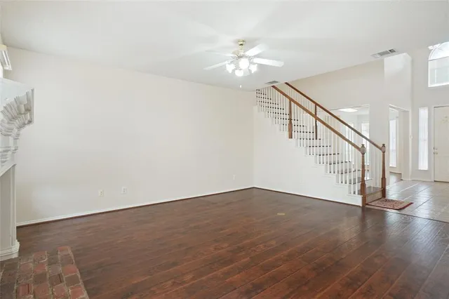 a view of an empty room with wooden floor and staircase